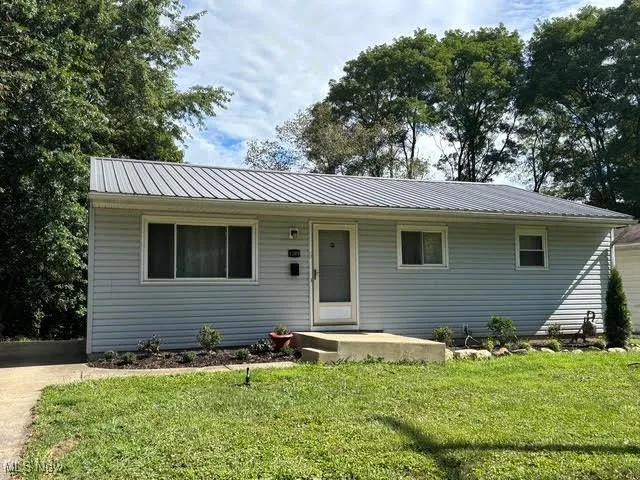 Single story home with a front lawn and a metal roof