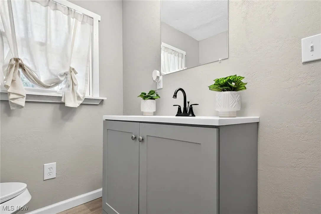 Half bathroom with a textured wall, vanity, and light wood-style flooring