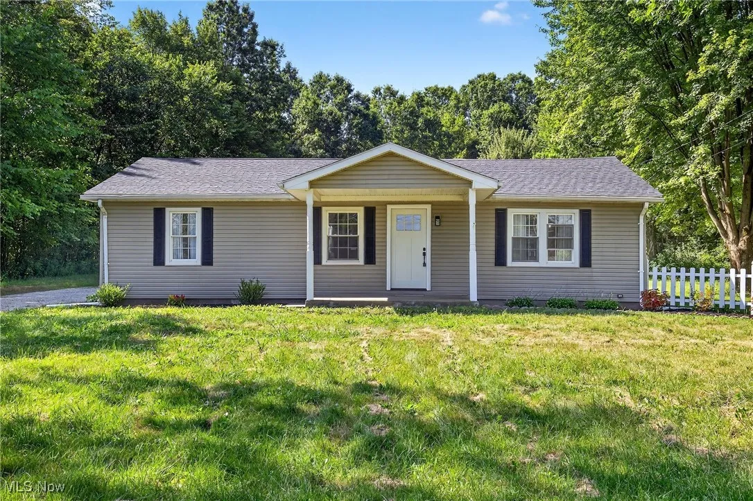 Ranch-style home with a porch, roof with shingles, and a front yard