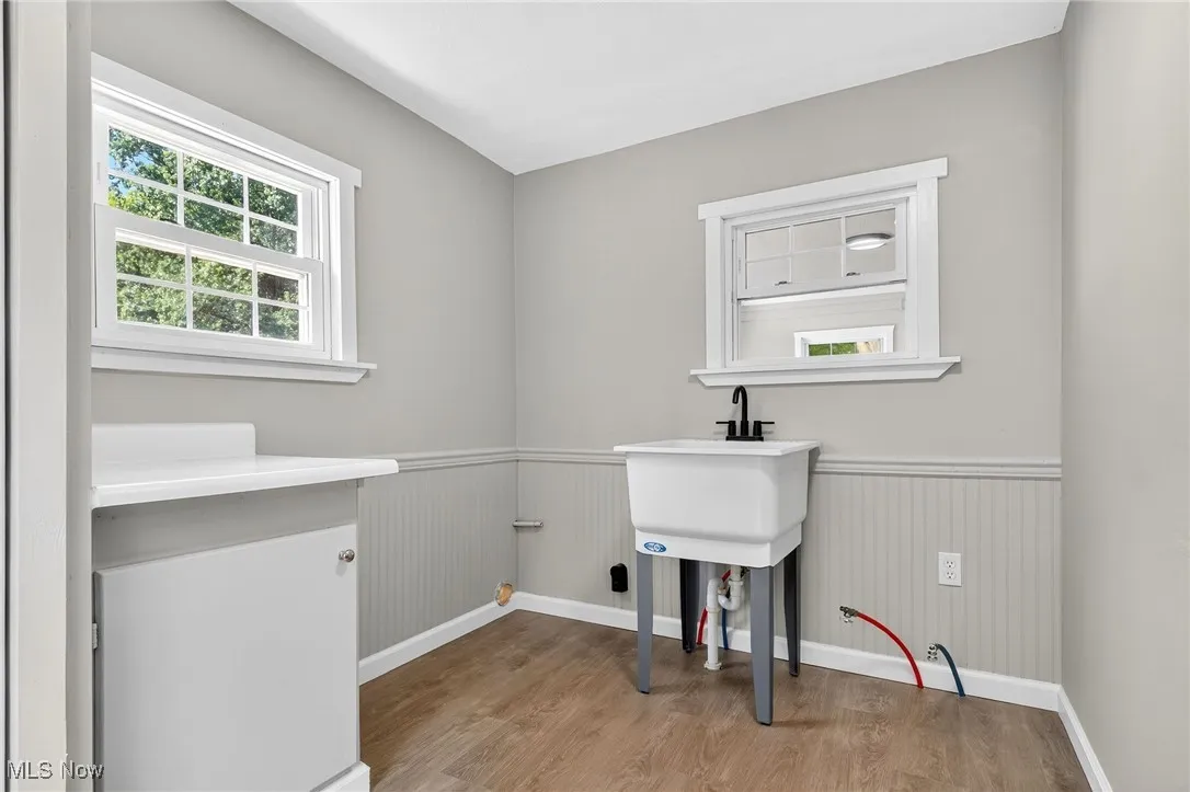 Laundry room featuring light wood finished floors, plenty of natural light, and a wainscoted wall