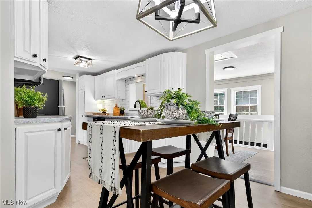 Kitchen with white cabinetry, decorative backsplash, a textured ceiling, light countertops, and light wood-style floors
