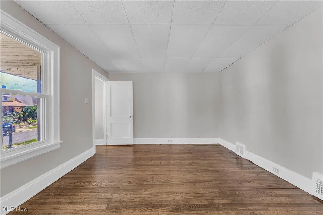 Empty room featuring dark wood-style floors and a paneled ceiling