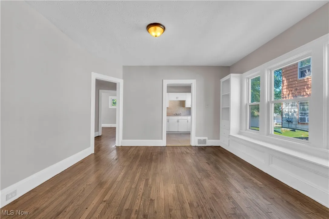 Empty room featuring dark wood finished floors and baseboards
