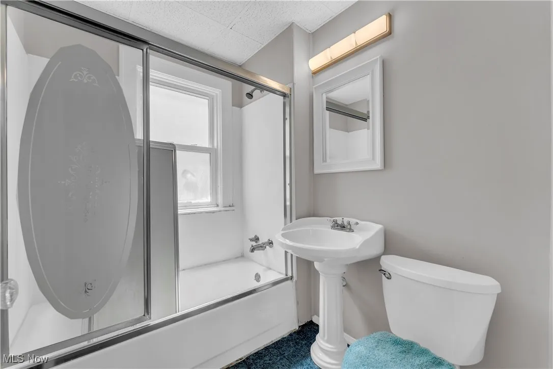 Full bathroom with combined bath / shower with glass door and toilet