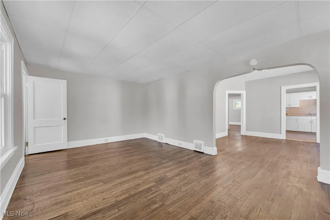 Spare room featuring arched walkways, wood finished floors, and a paneled ceiling
