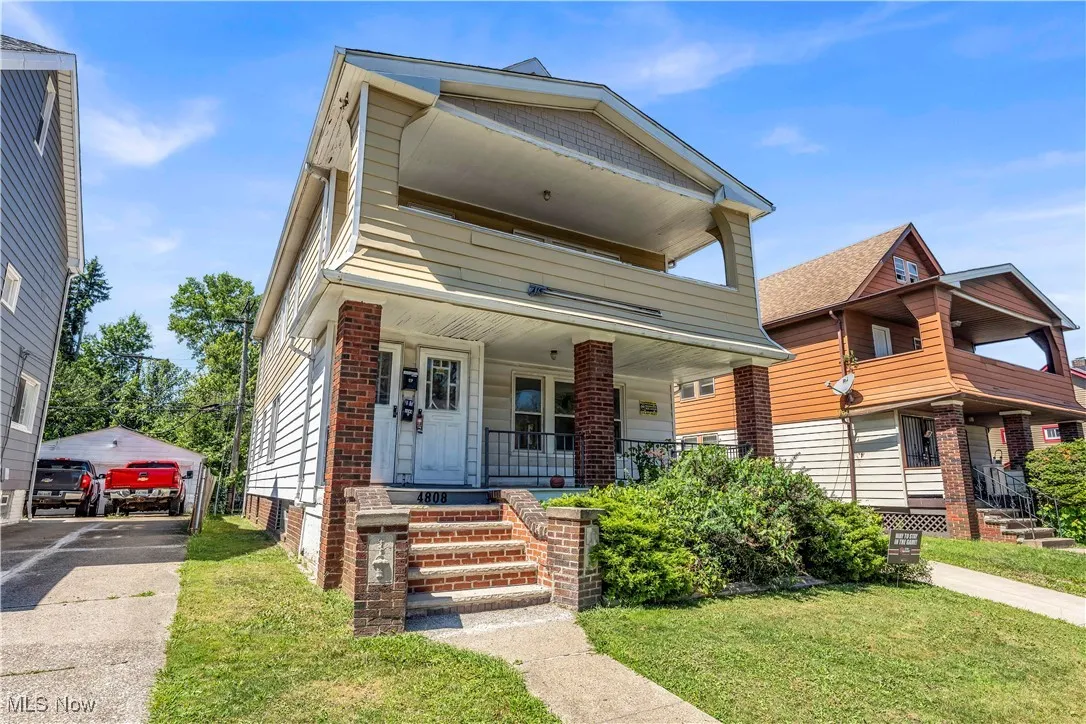 View of front of home with an outdoor structure, covered porch, a front yard, and a balcony