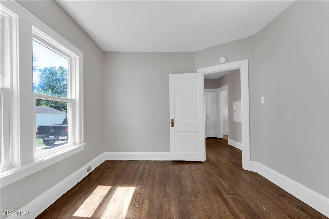Empty room featuring dark wood-type flooring and baseboards