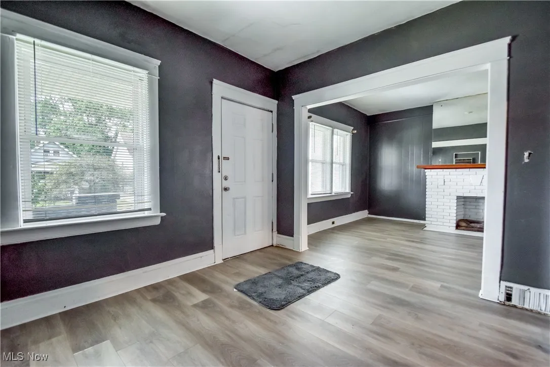 Entrance foyer with light wood-style floors and a brick fireplace