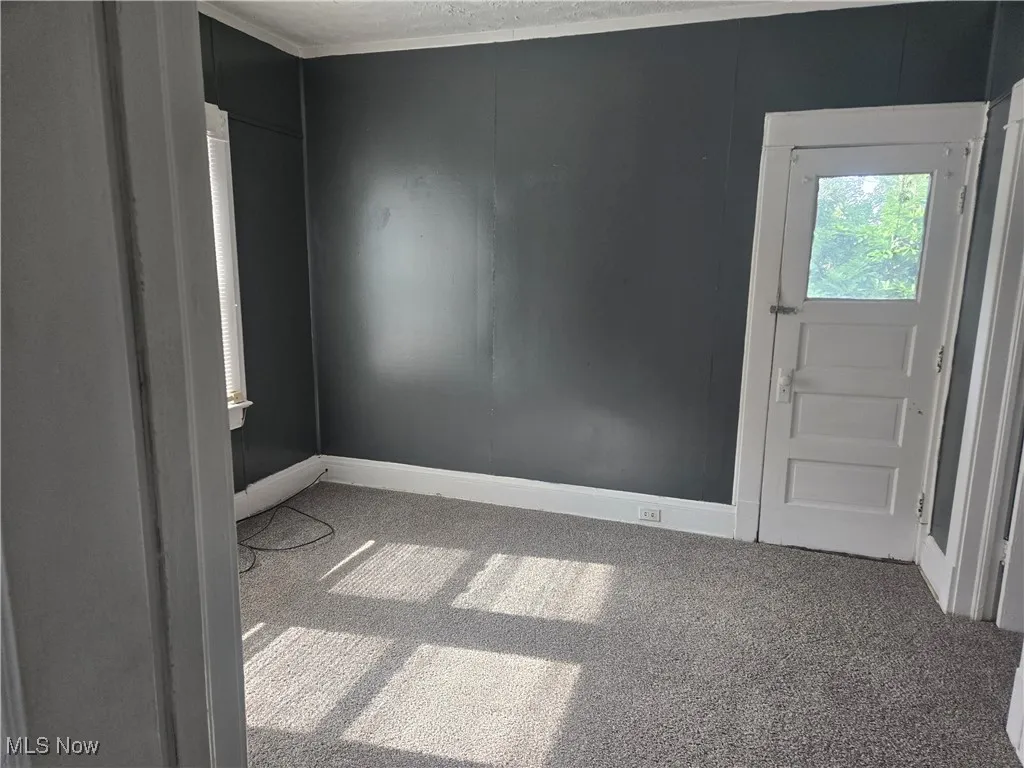 Carpeted spare room featuring baseboards