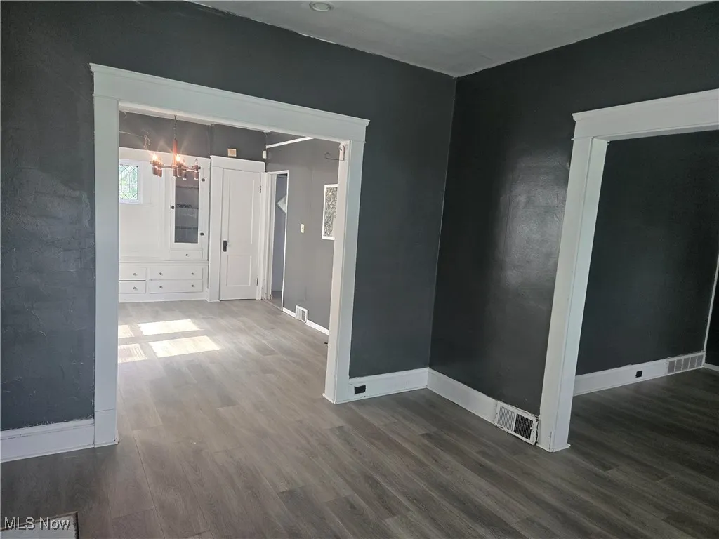 Spare room featuring dark wood-style floors and a chandelier