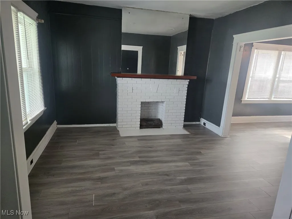 Unfurnished living room featuring a brick fireplace and wood finished floors