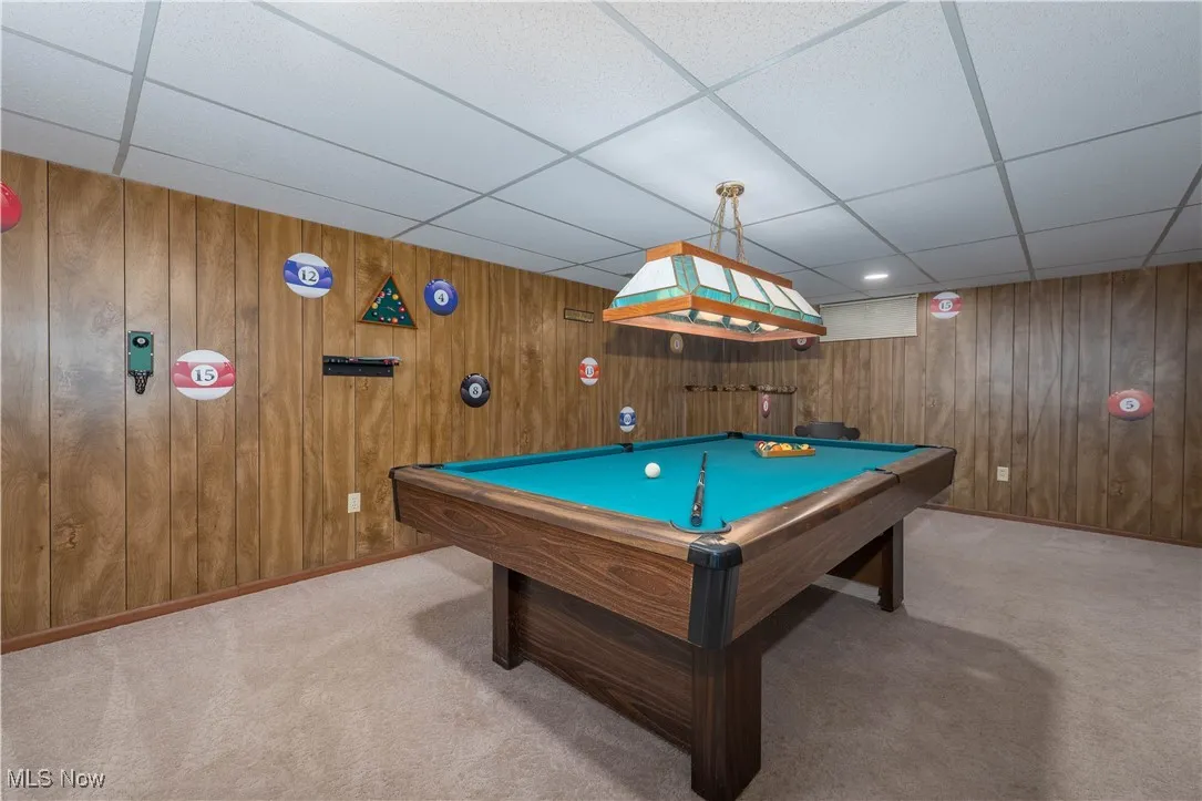 Playroom featuring pool table, a drop ceiling, wood walls, and carpet