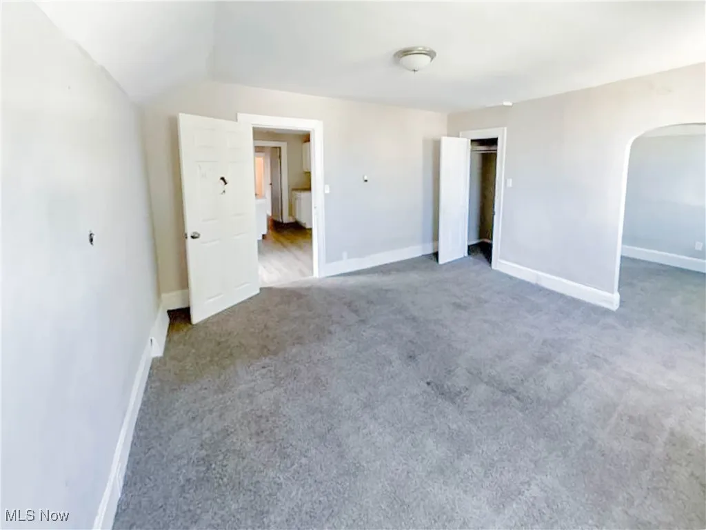 Unfurnished bedroom with arched walkways, carpet floors, and a closet