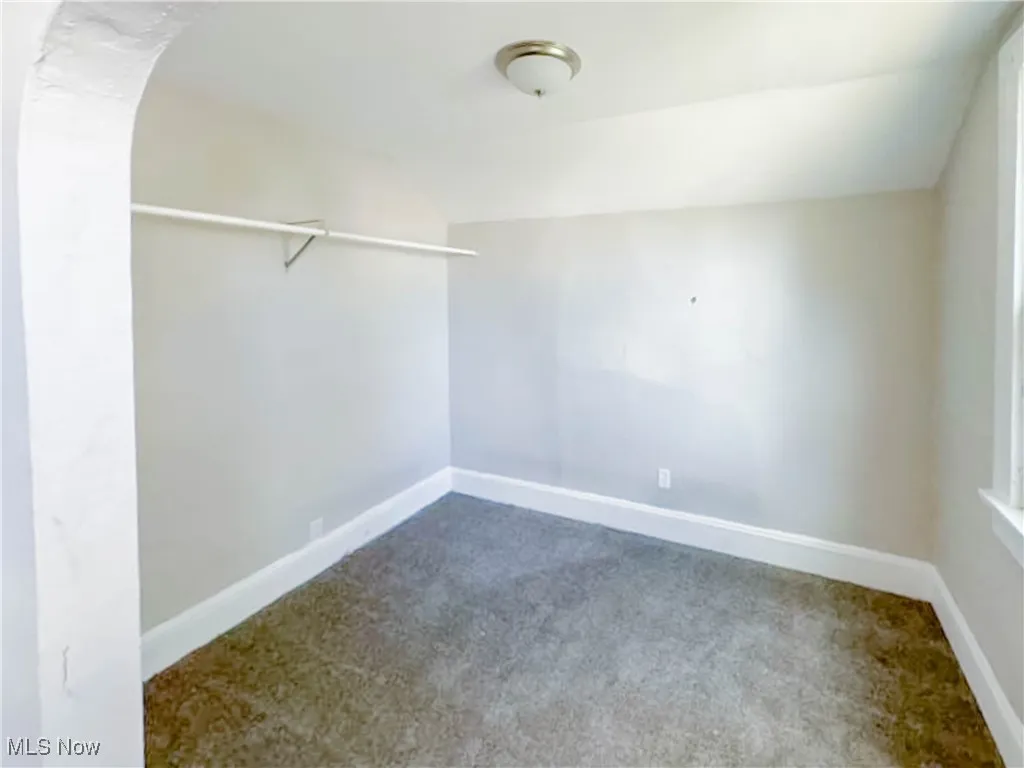 Bedroom with walk in closet with vaulted ceiling and carpet flooring