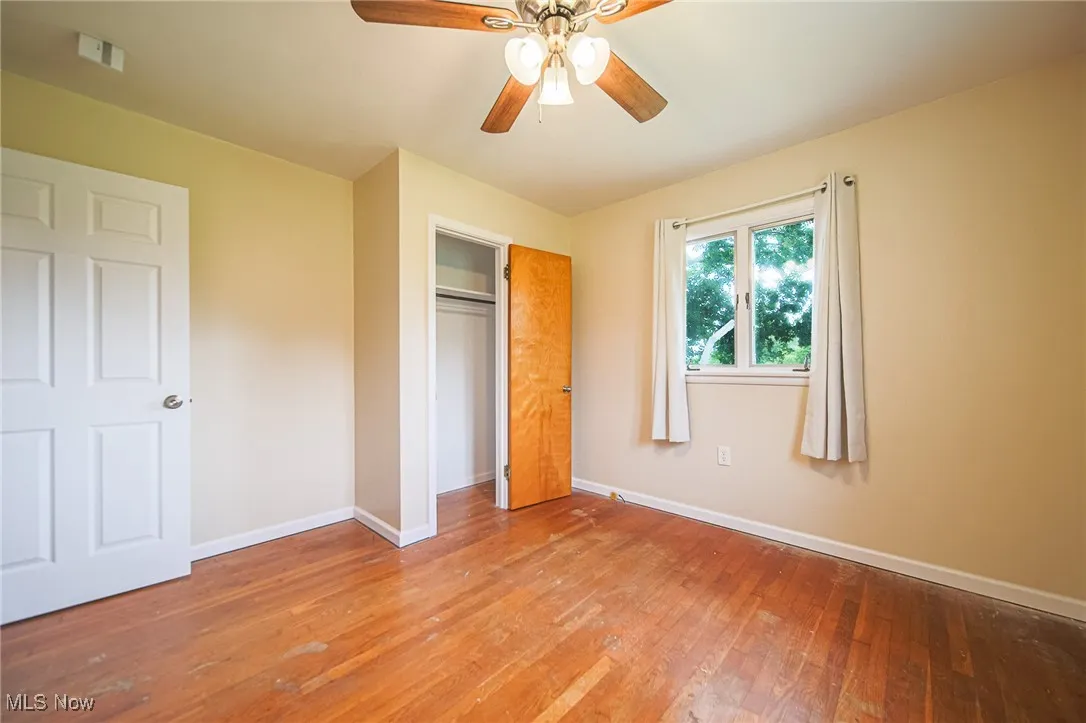 Unfurnished bedroom with hardwood / wood-style floors, a ceiling fan, and a closet