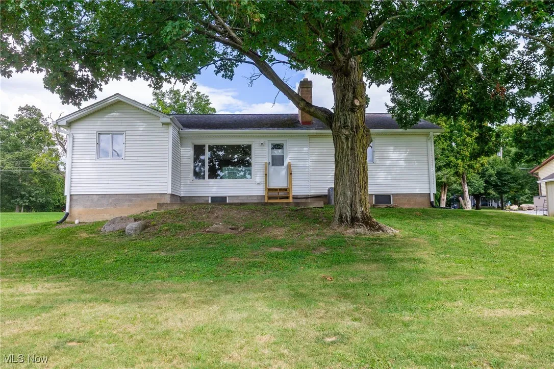 Rear view of property featuring a lawn, a chimney, and entry steps