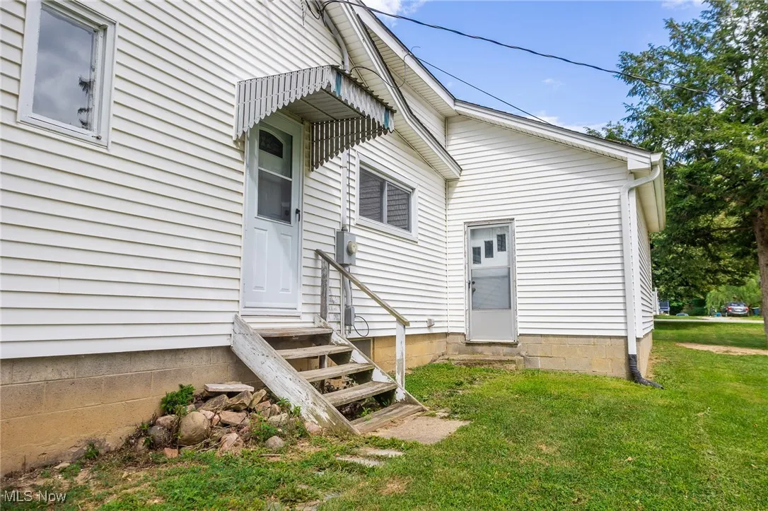 Rear view of house featuring entry steps and a lawn