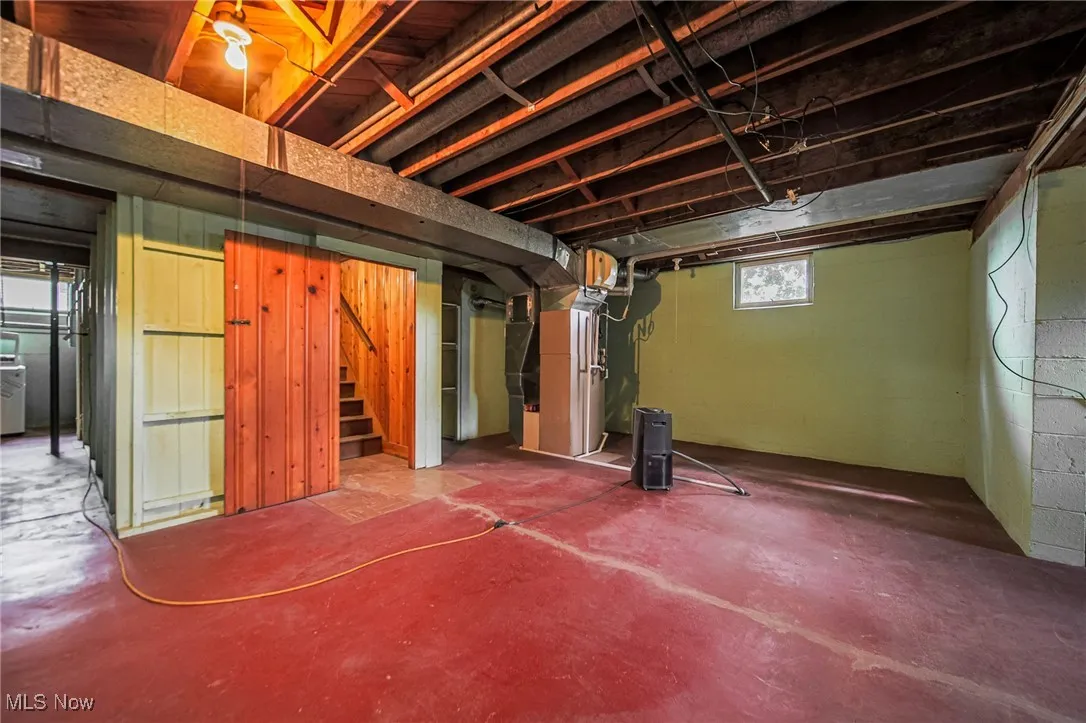Below grade area featuring heating unit and stairs