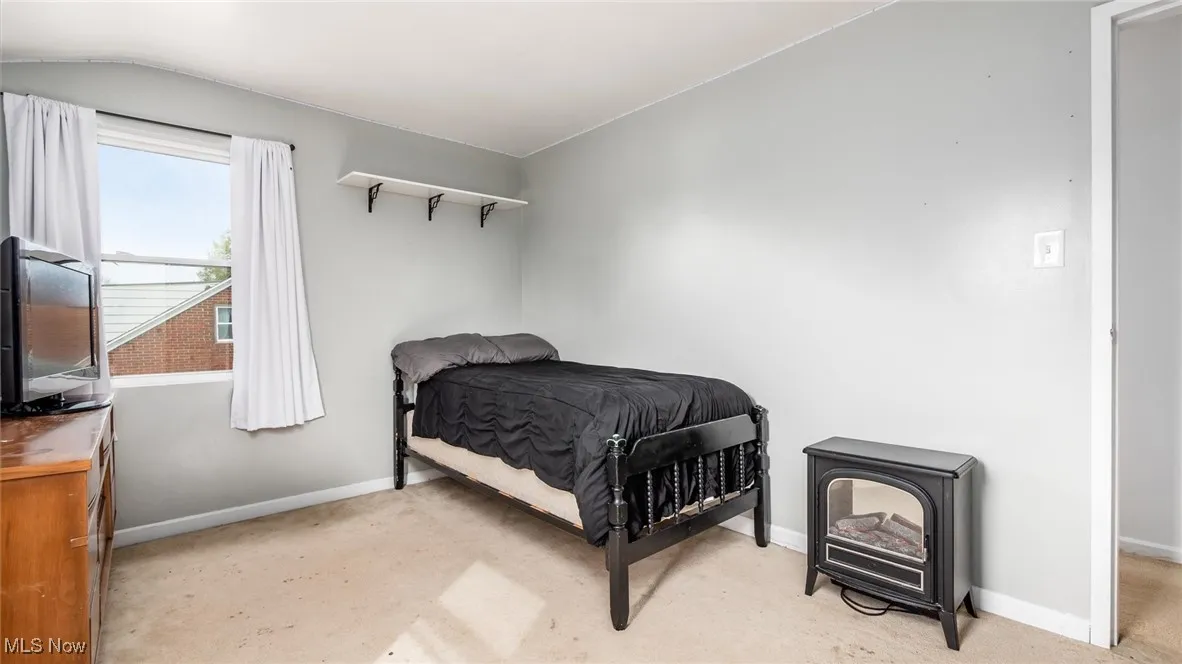 Bedroom with light carpet and a wood stove
