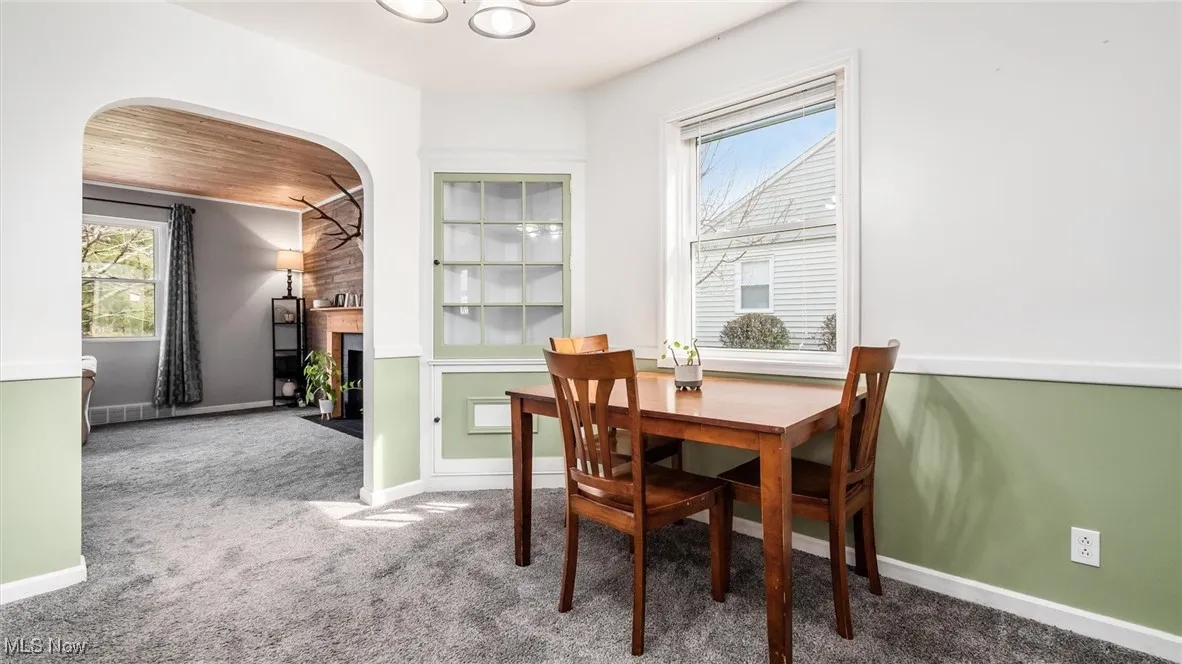 Dining room featuring carpet, a fireplace with flush hearth, arched walkways, and wooden ceiling