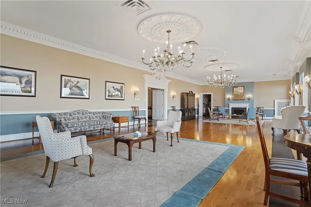 rentable community dining room with ornamental molding, light wood-style floors, a chandelier, and a fireplace