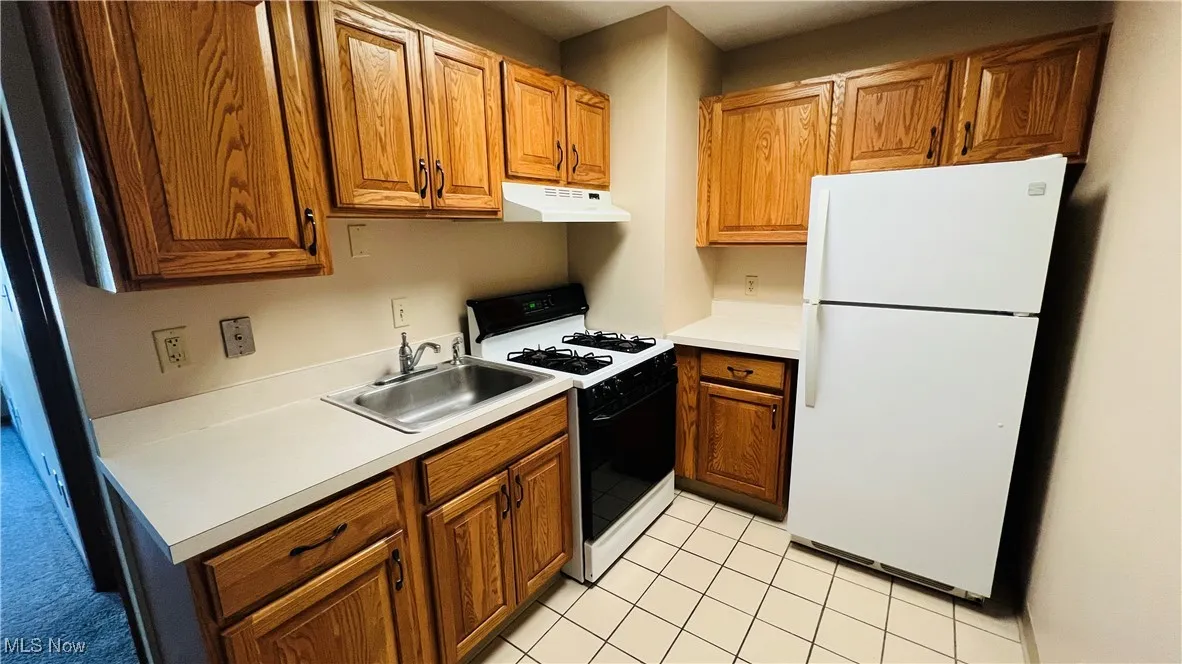 Kitchen with white appliances, brown cabinets, and light countertops