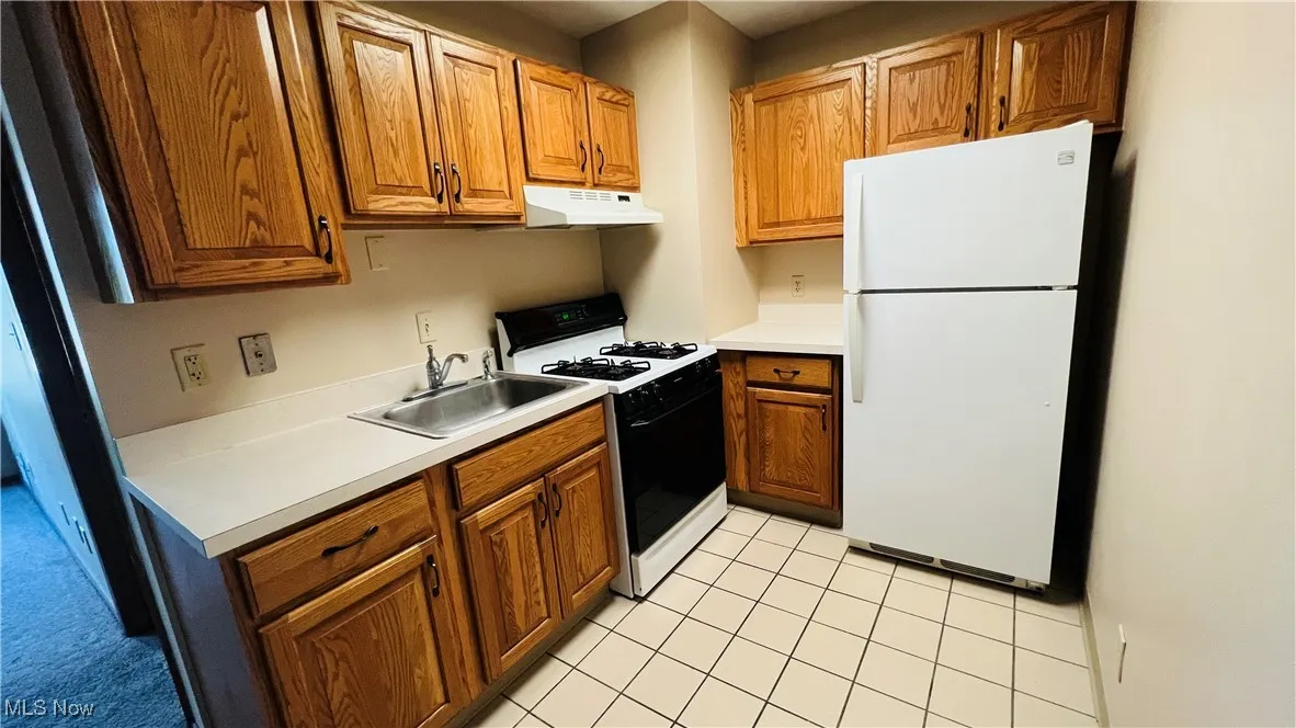 Kitchen with white appliances, light countertops, and brown cabinetry