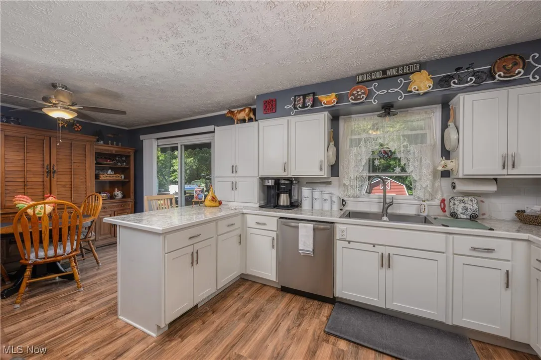 Kitchen with white cabinets, a peninsula, light countertops, and a textured ceiling