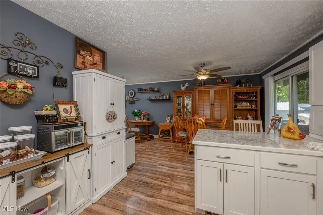 Kitchen featuring white cabinets, a peninsula, light countertops, a textured ceiling, and light wood-type flooring