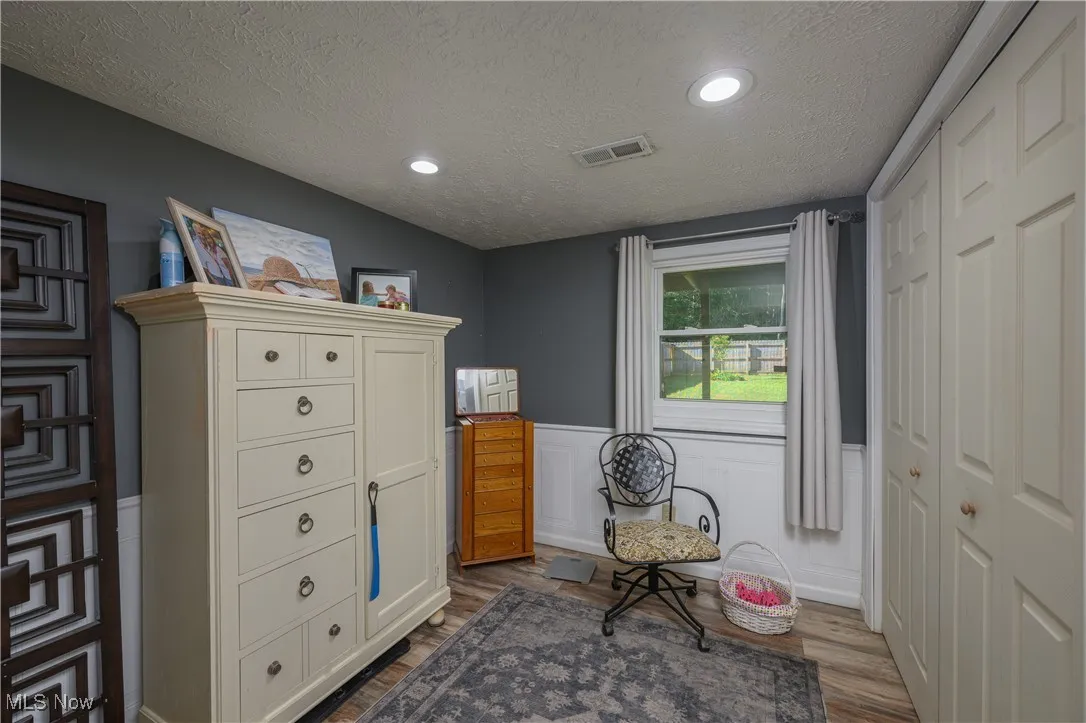 Sitting room featuring a wainscoted wall, a textured ceiling, dark wood finished floors, a decorative wall, and recessed lighting