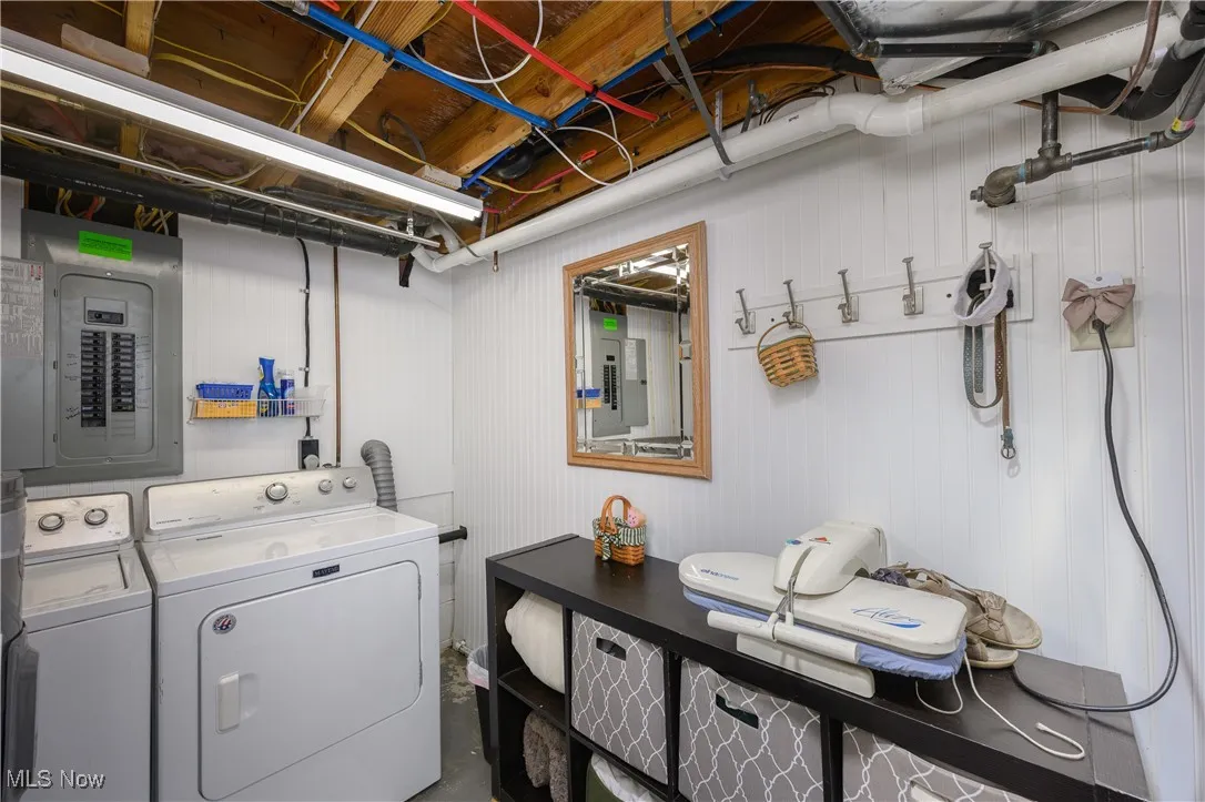 Laundry area featuring electric panel, independent washer and dryer, and wooden walls