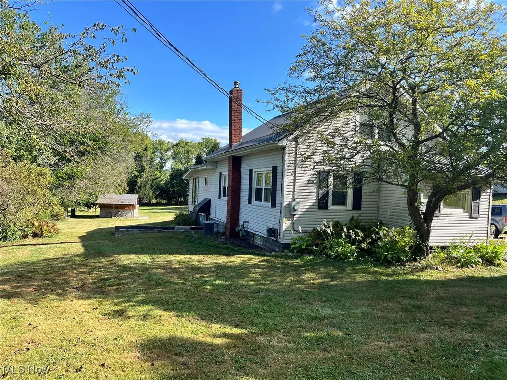 View of side of property featuring a lawn and a chimney