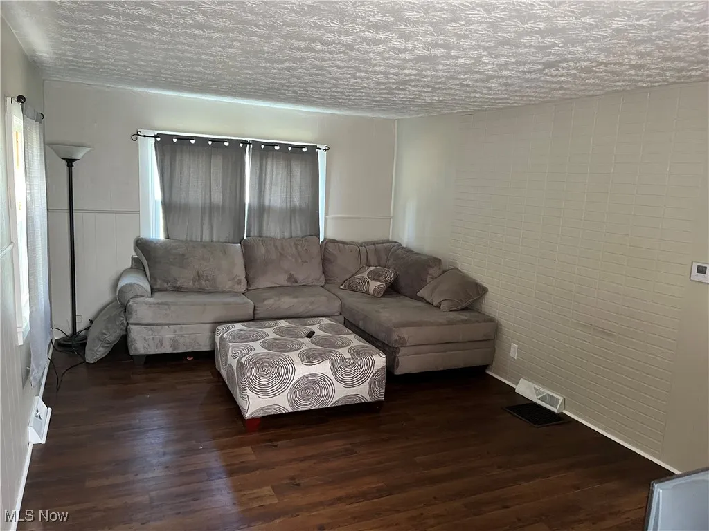 Living room with dark wood-style floors and a textured ceiling