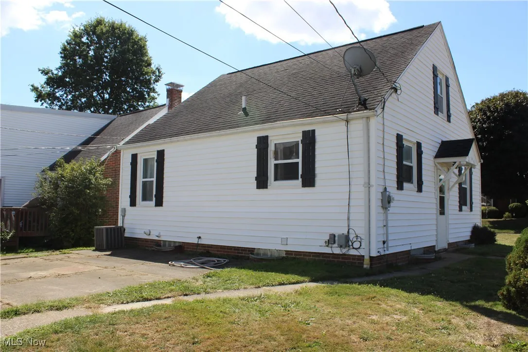View of home's exterior featuring roof with shingles, a chimney, and a lawn