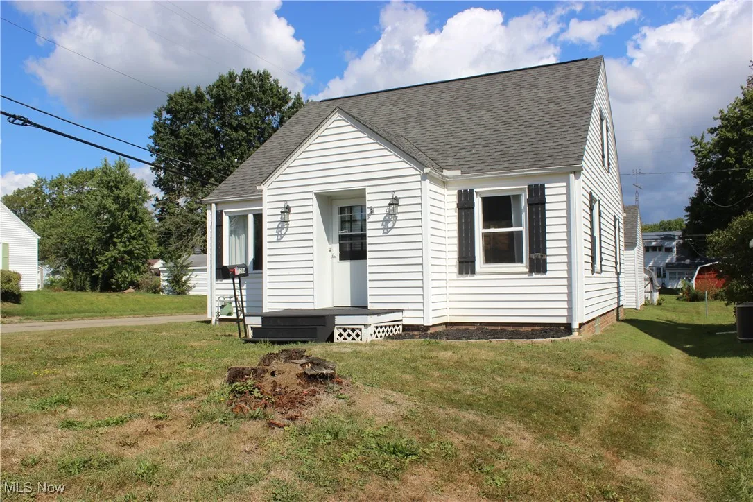 View of front facade with roof with shingles and a front lawn