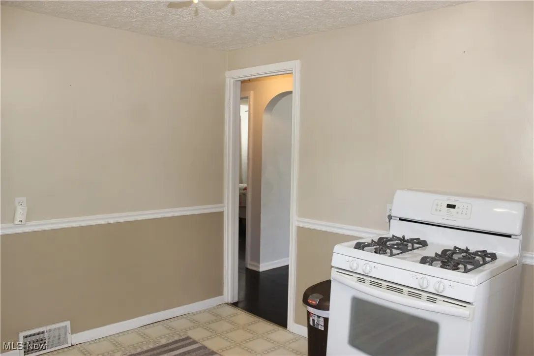 Kitchen with white range with gas stovetop, a textured ceiling, tile patterned floors, and ceiling fan