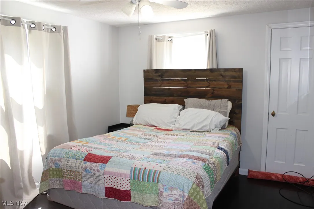 Bedroom with a textured ceiling and a ceiling fan