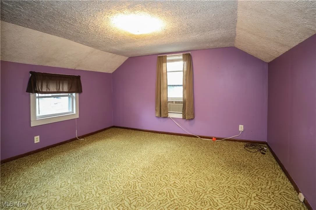 Bedroom with a textured ceiling, lofted ceiling, and carpet
