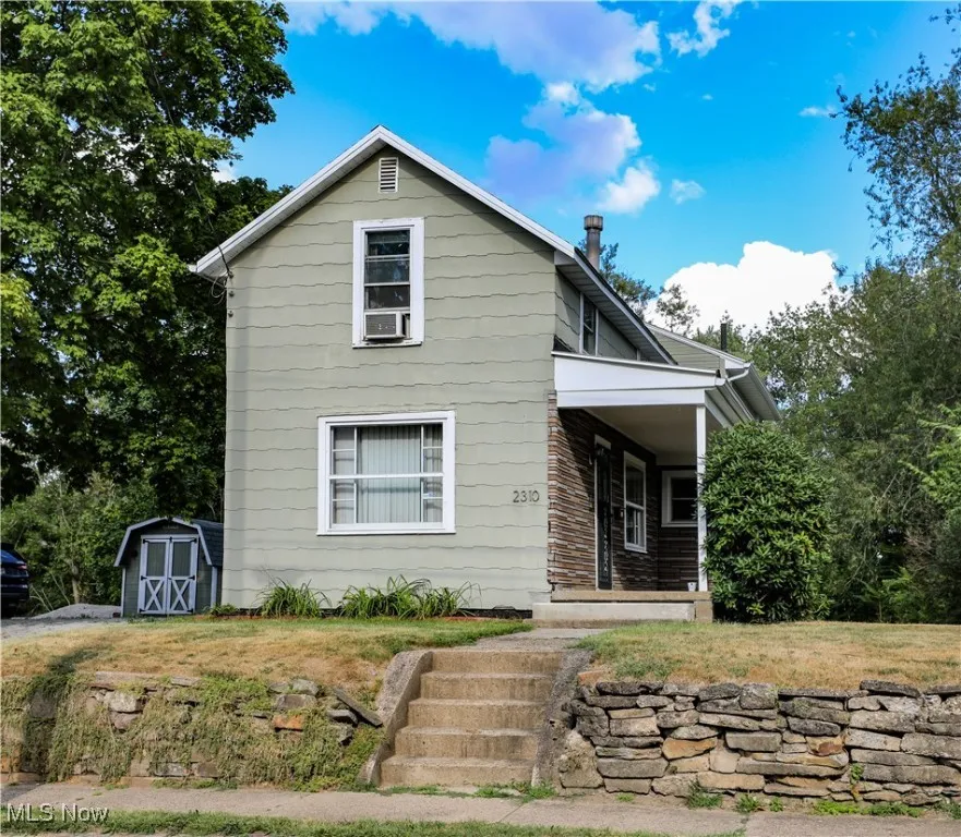 View of front of house featuring covered porch and a shed