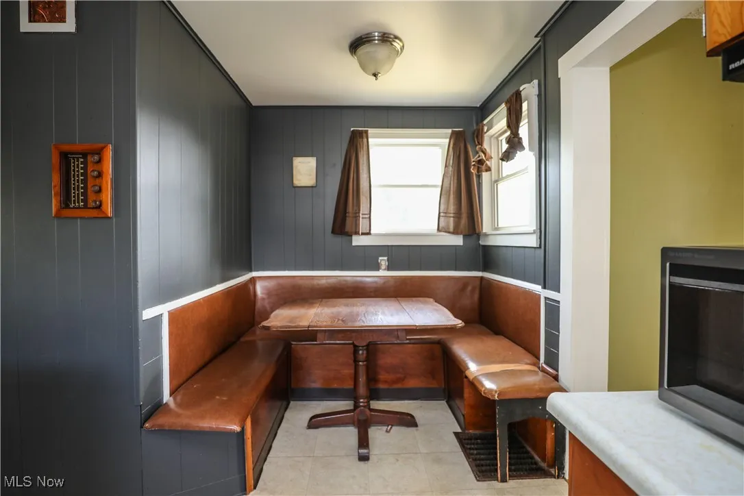 Dining space featuring breakfast area, wood walls, and light tile patterned floors