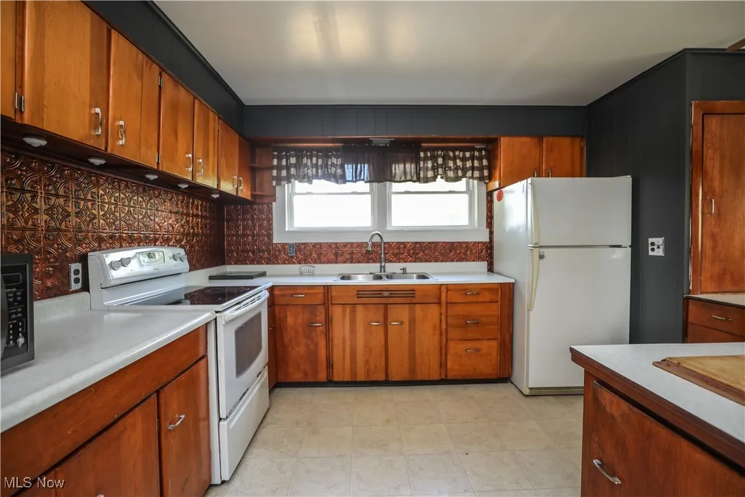 Kitchen featuring white appliances, light countertops, and brown cabinets