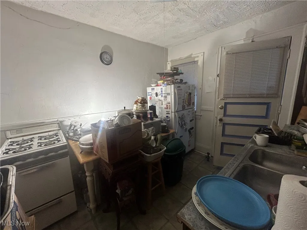 Kitchen with white appliances and a textured ceiling
