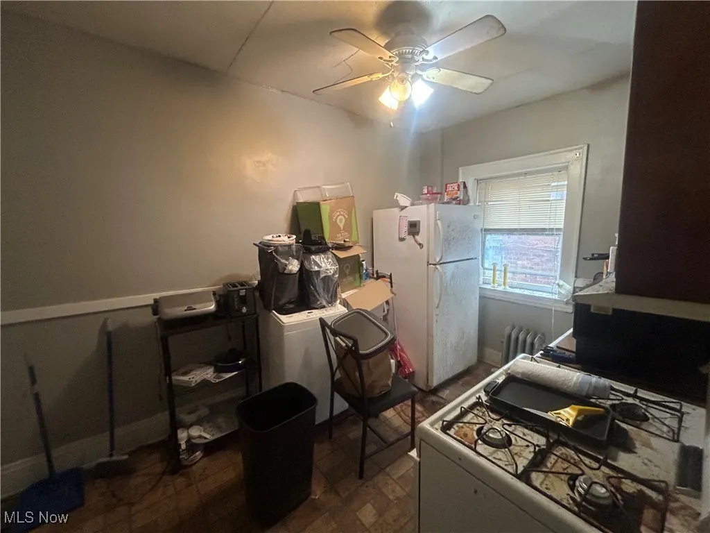 Kitchen with white appliances, radiator heating unit, and ceiling fan