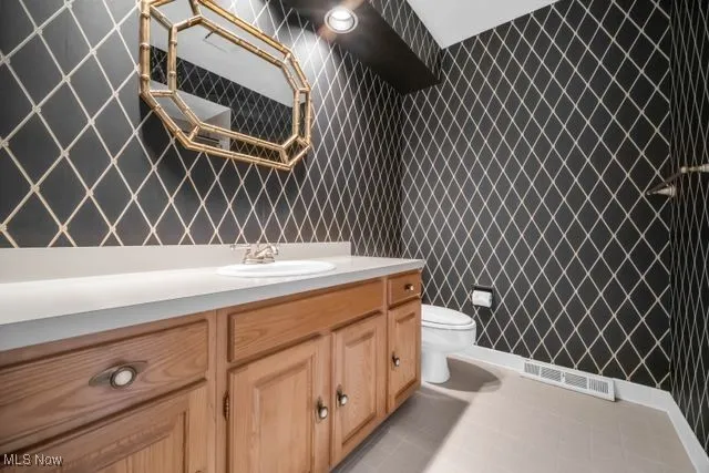 Bathroom featuring vanity, toilet, shower over tub