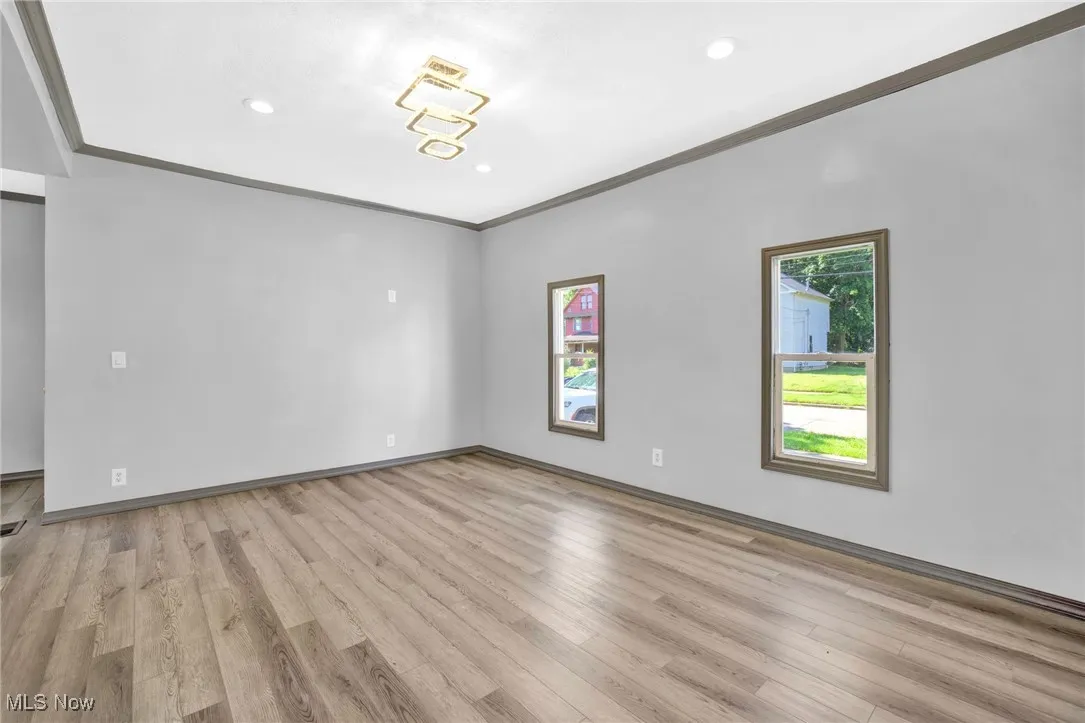 Empty room featuring crown molding, light wood-type flooring, and recessed lighting