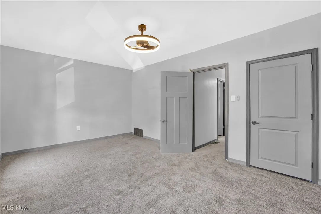 Unfurnished bedroom with vaulted ceiling, light carpet, and a skylight