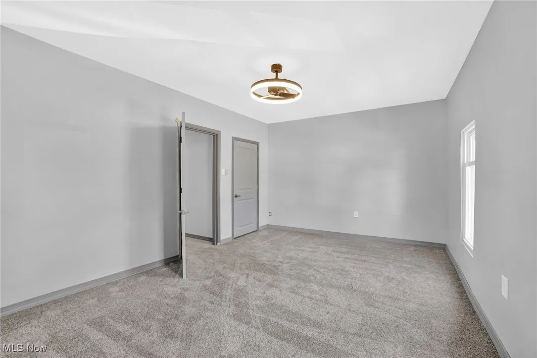 Empty room with light colored carpet and baseboards