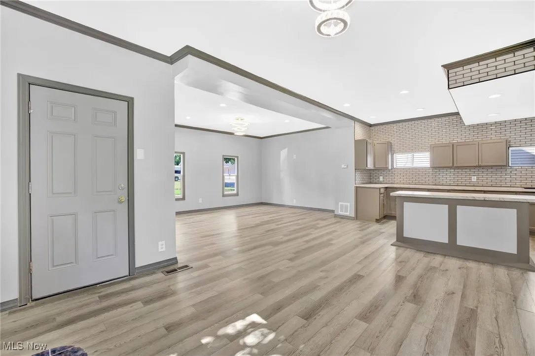 Unfurnished living room with crown molding, healthy amount of natural light, light wood-type flooring, and recessed lighting