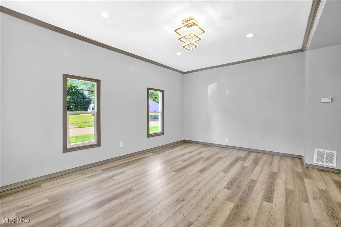 Empty room featuring crown molding, light wood-type flooring, and recessed lighting