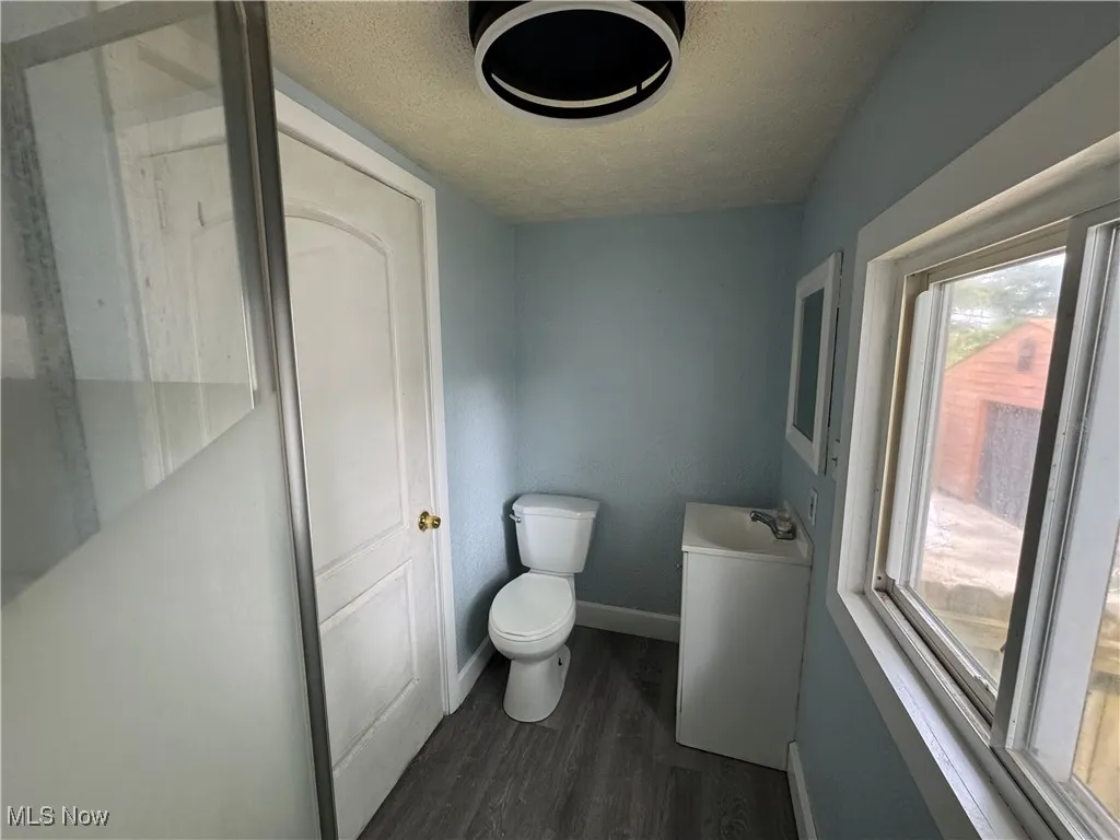 Main Floor Full Bathroom with a textured ceiling and dark wood-type flooring